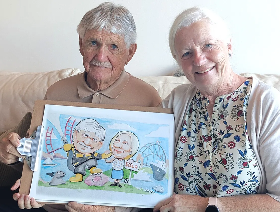 Elderly couple holding up the watercolour caricature of themselves